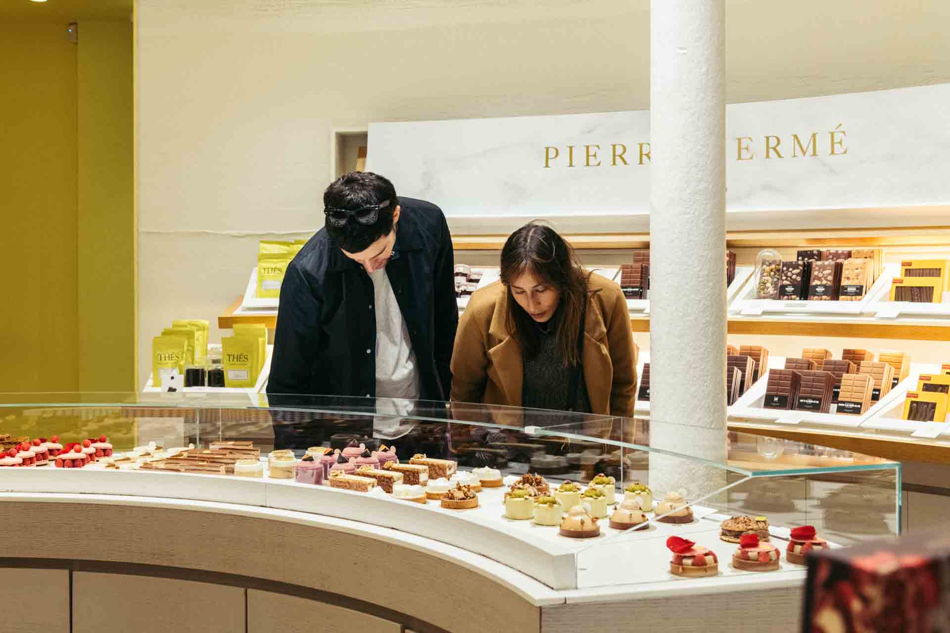 people_looking_at_macarons_on_a_shelf_Pierre_Hermé_Paris